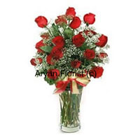 Beauty at its finest, these 24 red roses are put together in an impressive bunch along with seasonal flowers and fillers in a glass vase. The display is kept natural and simple. The lean tall glass vase adds to bunch looking fuller and plumper. Meanwhile a golden satin bow wrapped around the glass adds the zing element. This one looks perfect in any corner of the room and goes well for every occasion.
