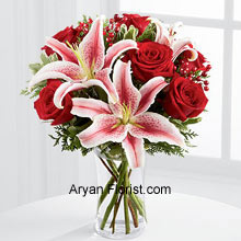A stunning display of divinity through these Rich red roses and dazzling beauty of lilies will spread the sanctity of the festivities. These divine and elegant combination is further accentuated with holiday greens, berry sprays, and a Bordeaux satin ribbon. A cylindrical clear glass vase holds these beauties with pride and spirituality. Embracing this season with this formidable collection and wish everyone the augment of the lovely season comprising of happiness and joy! (Please Note That We Reserve the Right to Substitute any Product with a Suitable Product of Equal Value in Case of Non-Availability of a Certain Product)