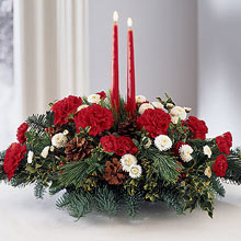 A soothing combination of red carnations and white Gerberas are apt for this season of merrymaking. The two red taper candles add to the charm of this arrangement that can be used as a centerpiece. The red signifies warmth and love, whereas the white embodies the feeling of peace and tranquility, each balancing the extremity of the other. This is the true spirit of Christmas as love is the central theme of the festival. (Please Note That We Reserve the Right to Substitute any Product with a Suitable Product of Equal Value in Case of Non-Availability of a Certain Product)